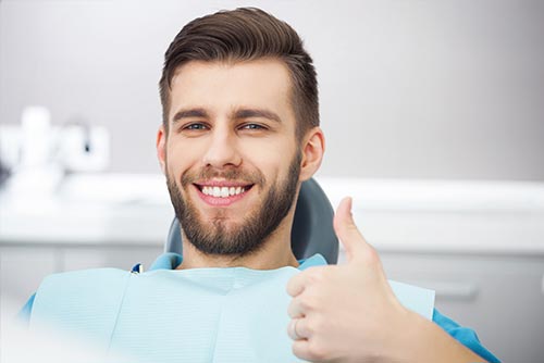 Stock image of a patient smiling after receiving routine dental cleanings.